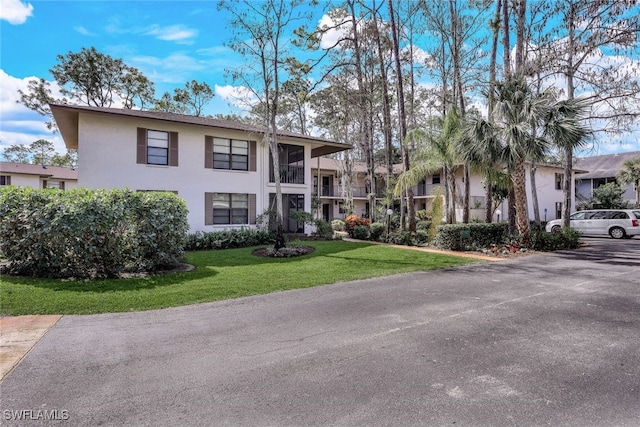 view of front of property featuring a front yard and a balcony