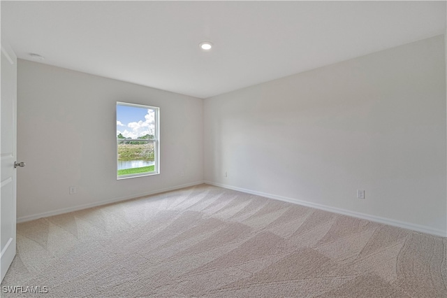 unfurnished room featuring light carpet and a water view