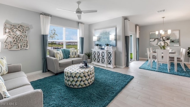 living room featuring ceiling fan with notable chandelier and light wood-type flooring