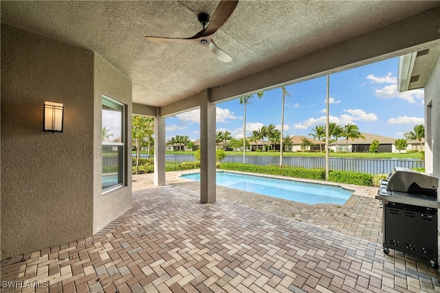 view of pool with a water view, ceiling fan, a patio area, and a grill