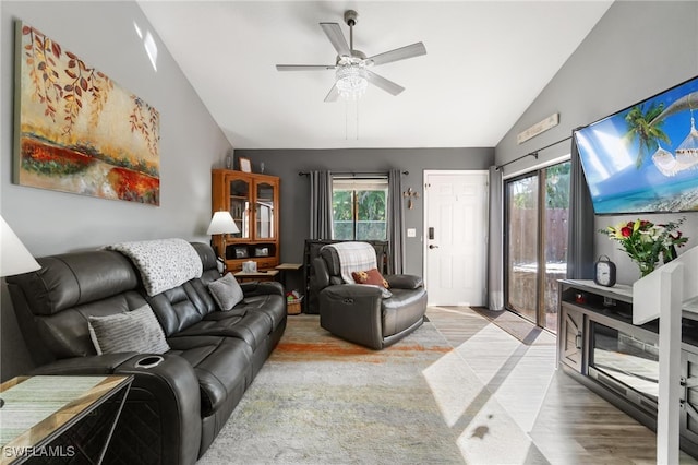 living room featuring light hardwood / wood-style flooring, vaulted ceiling, ceiling fan, and plenty of natural light