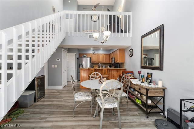 dining area featuring hardwood / wood-style flooring, a towering ceiling, and a notable chandelier