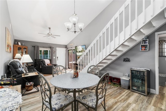 dining room featuring ceiling fan with notable chandelier, vaulted ceiling, light hardwood / wood-style flooring, and wine cooler