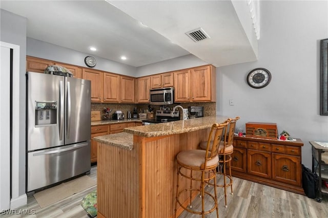 8913 Somerset Blvd, Fort Myers, FL 33919 - kitchen with stainless steel appliances, a peninsula, light wood-style floors, and light stone counters