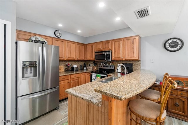 8913 Somerset Blvd, Fort Myers, FL 33919 - kitchen with light stone counters, a sink, a peninsula, appliances with stainless steel finishes, and visible vents
