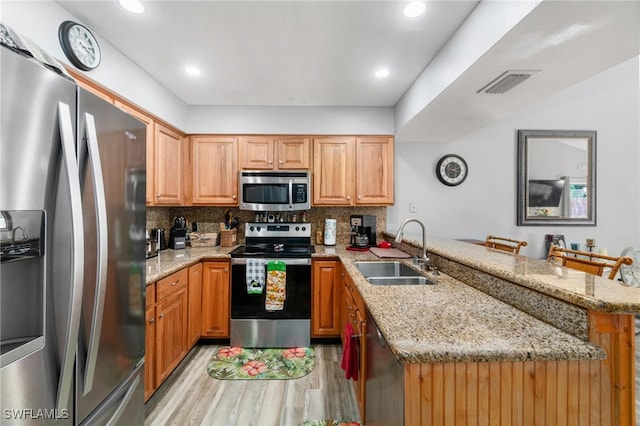 kitchen featuring sink, kitchen peninsula, appliances with stainless steel finishes, a kitchen bar, and decorative backsplash