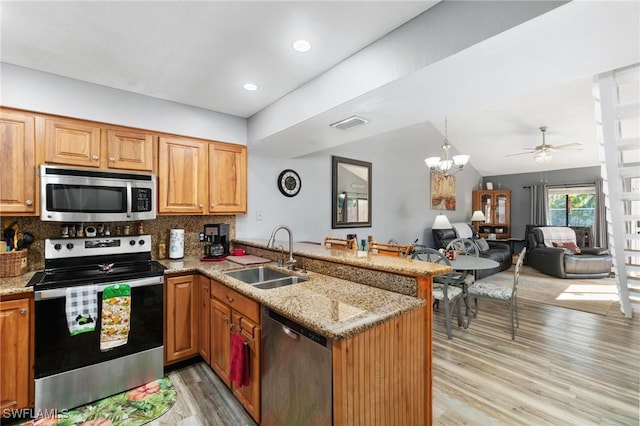 kitchen with tasteful backsplash, sink, vaulted ceiling, kitchen peninsula, and stainless steel appliances