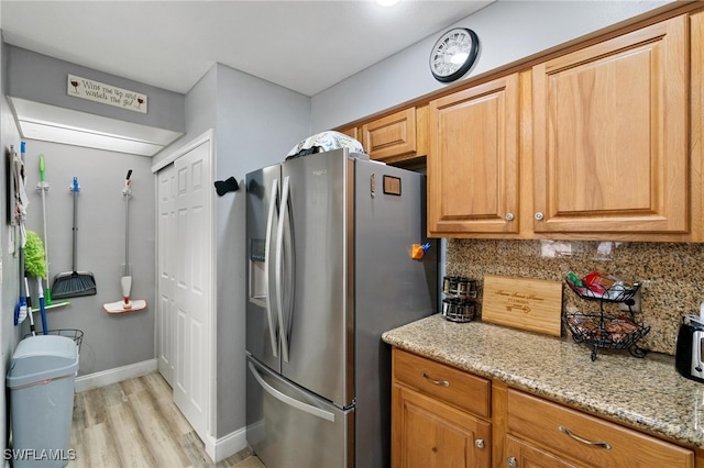 kitchen featuring light stone counters, backsplash, light hardwood / wood-style floors, and stainless steel fridge with ice dispenser