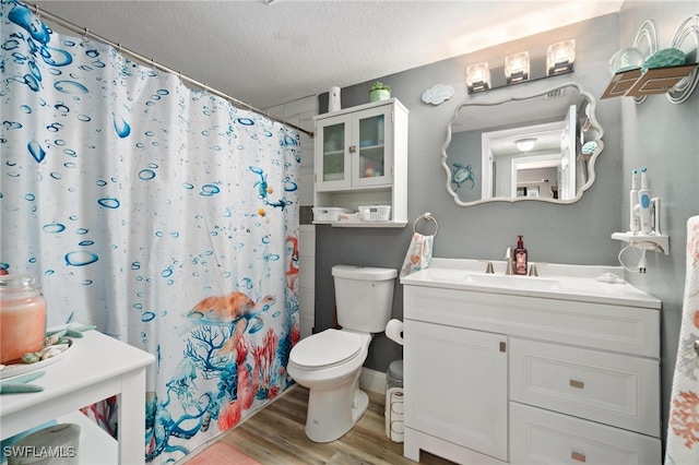 bathroom with vanity, a textured ceiling, hardwood / wood-style flooring, walk in shower, and toilet