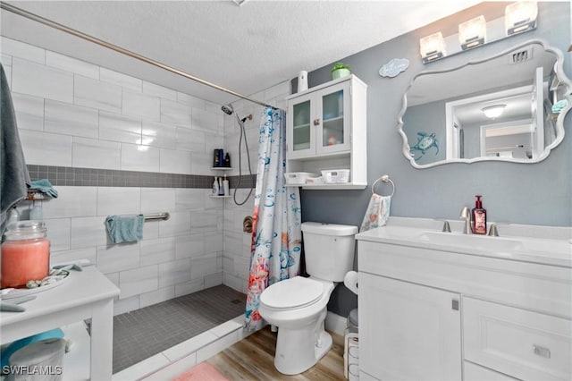 8913 Somerset Blvd, Fort Myers, FL 33919 - bathroom featuring wood finished floors, a textured ceiling, vanity, a tile shower, and toilet