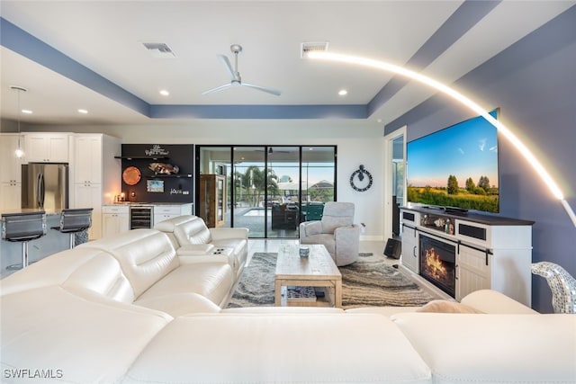 cinema room with wine cooler, ceiling fan, and a raised ceiling