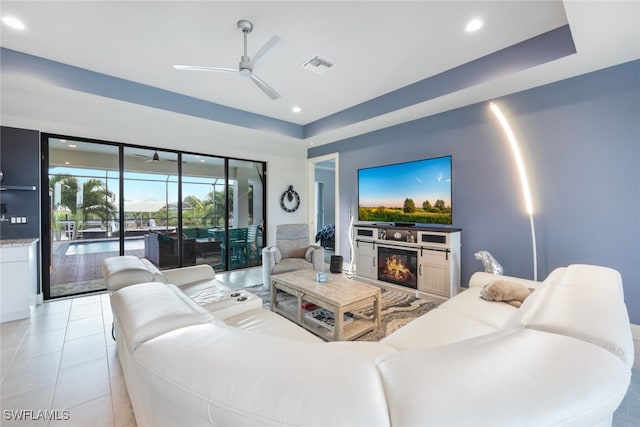 living room featuring a fireplace, light tile patterned flooring, and ceiling fan