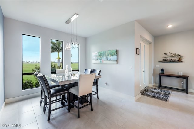 tiled dining room featuring an inviting chandelier and a healthy amount of sunlight