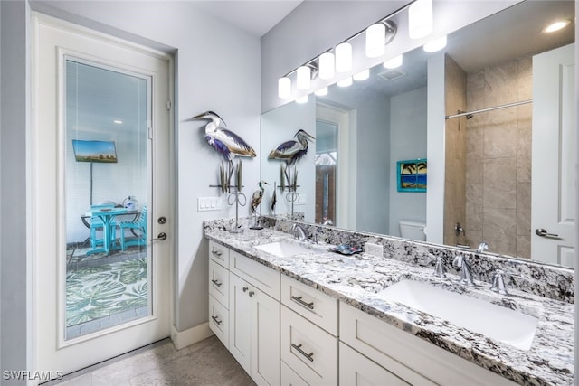 bathroom with tiled shower, vanity, and toilet