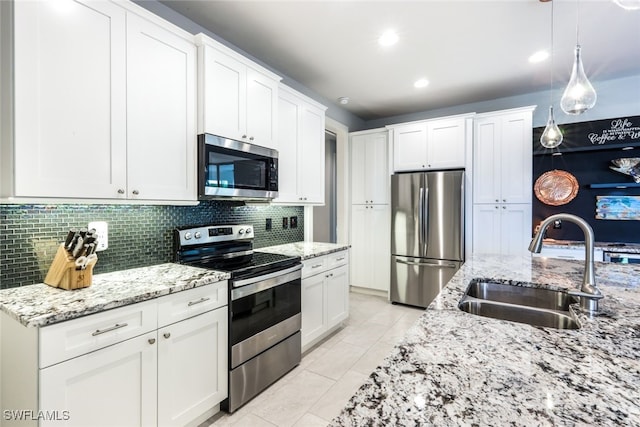 kitchen featuring white cabinets, hanging light fixtures, sink, tasteful backsplash, and stainless steel appliances