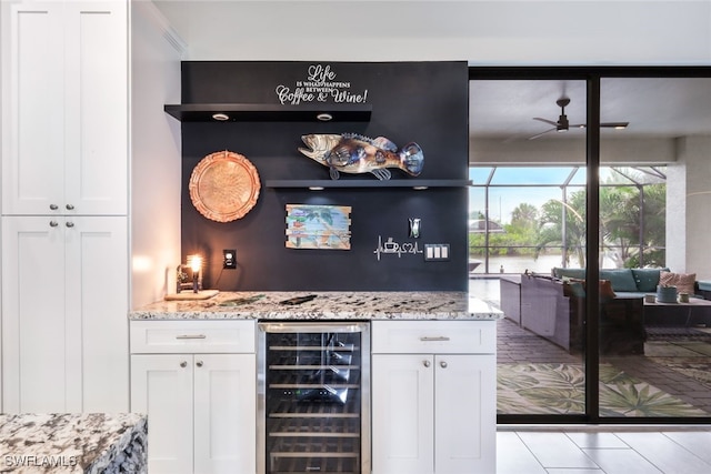 bar with ceiling fan, wine cooler, light stone countertops, and white cabinetry