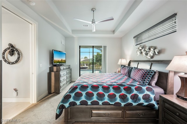 bedroom featuring a tray ceiling, light carpet, ceiling fan, and access to exterior