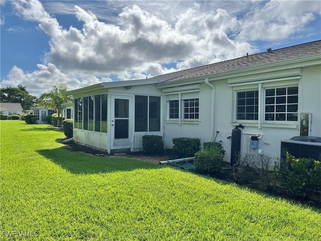 rear view of house featuring a sunroom, a yard, and central air condition unit