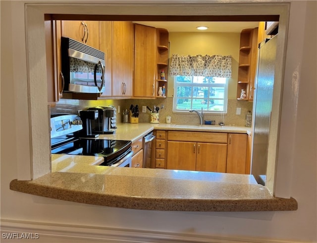 kitchen featuring backsplash, sink, light stone countertops, and stainless steel appliances