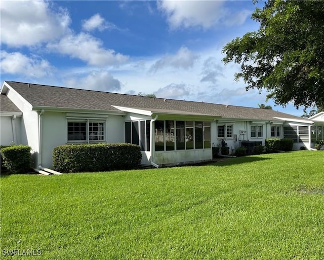 rear view of house featuring a yard and a sunroom