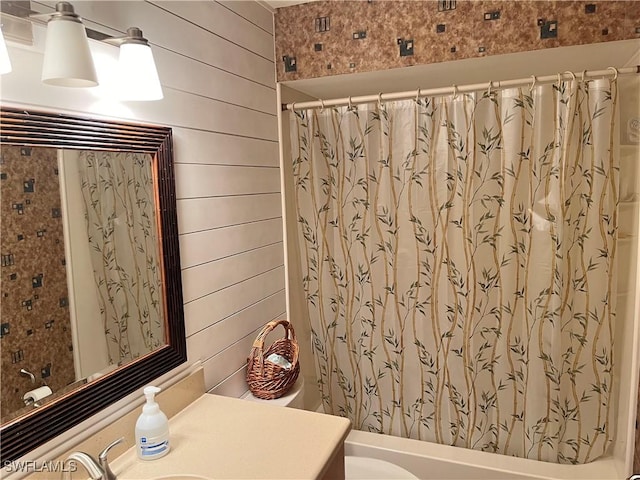 full bathroom featuring vanity, toilet, wooden walls, and shower / tub combo