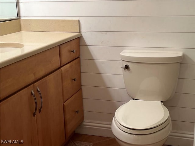 bathroom with wooden walls, vanity, and toilet