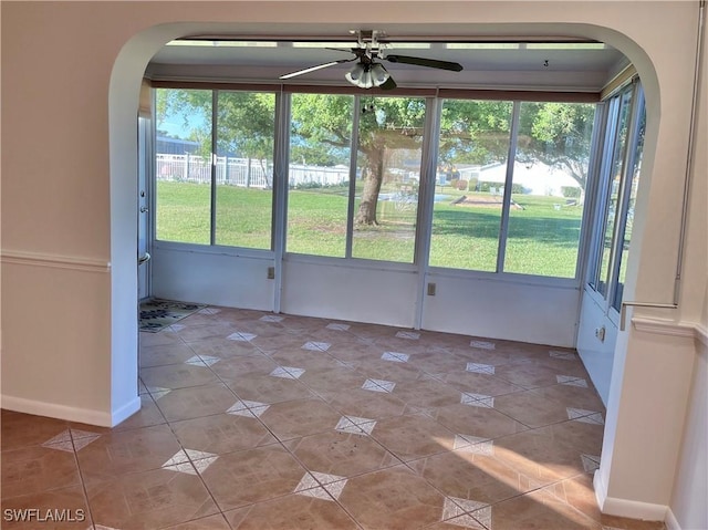 unfurnished sunroom featuring ceiling fan and plenty of natural light