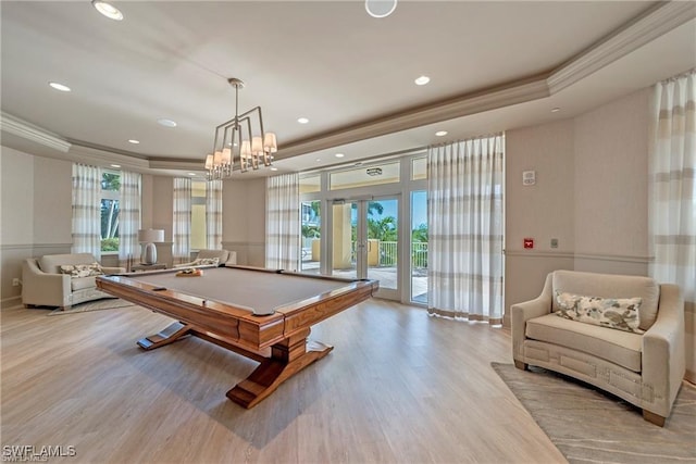 recreation room featuring billiards, ornamental molding, light hardwood / wood-style floors, a raised ceiling, and plenty of natural light