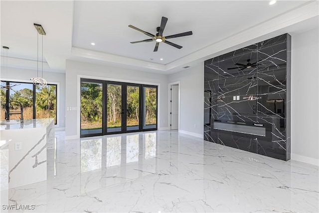 interior space with marble finish floor, plenty of natural light, a tray ceiling, and recessed lighting