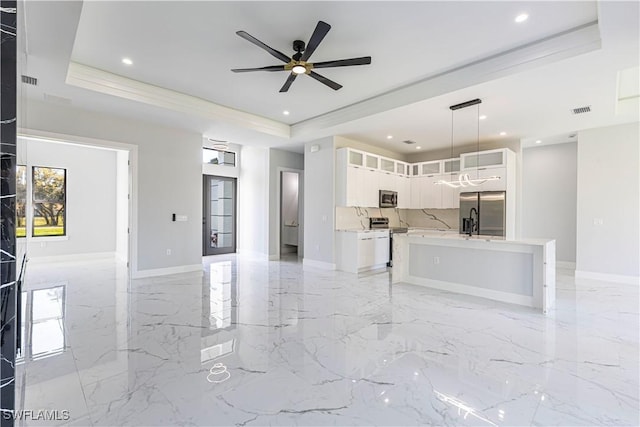 kitchen with a tray ceiling, stainless steel appliances, light countertops, visible vents, and white cabinets