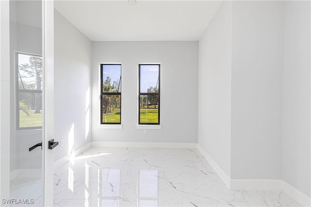 spare room featuring marble finish floor and baseboards