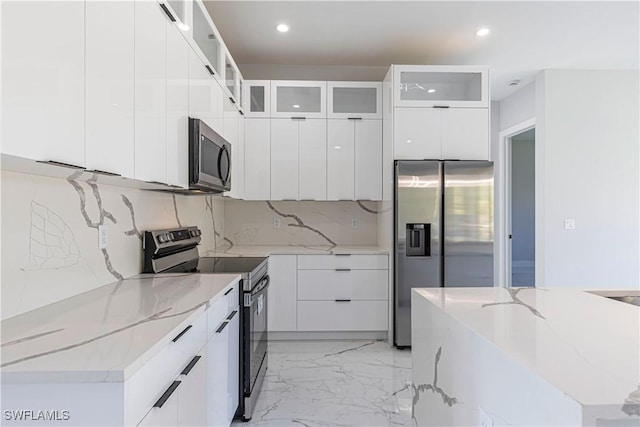 kitchen featuring marble finish floor, stainless steel appliances, modern cabinets, and white cabinetry