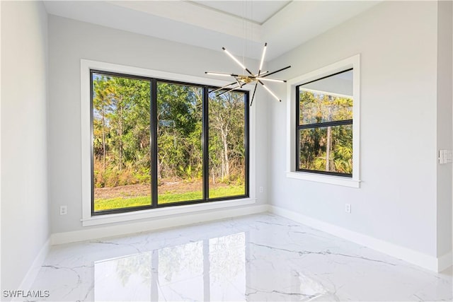 empty room with a chandelier, marble finish floor, and baseboards