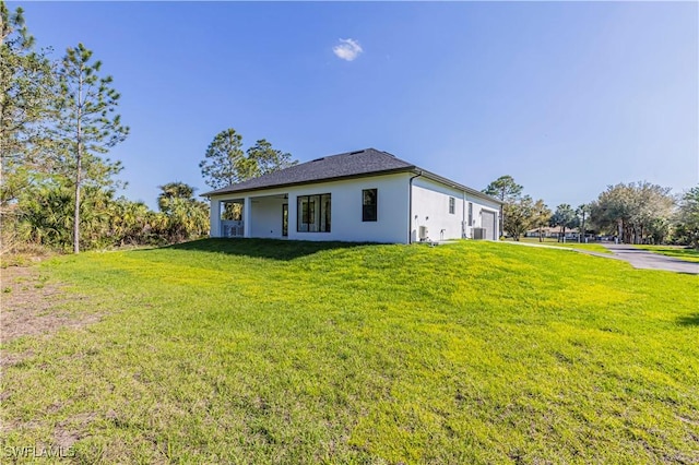 exterior space with a lawn, an attached garage, and stucco siding