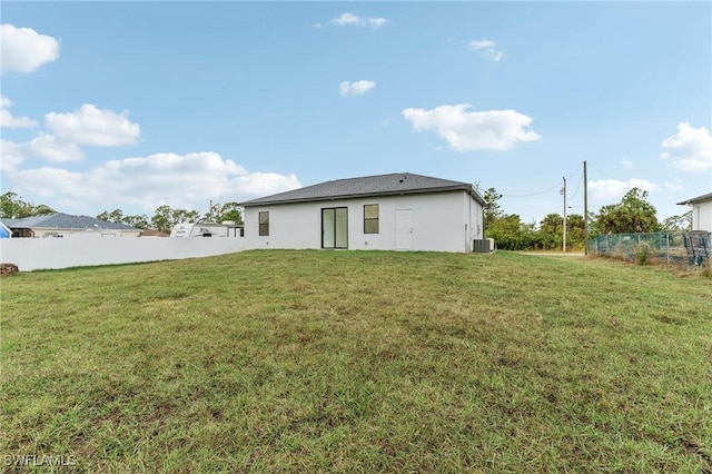 rear view of property featuring a yard and central AC unit