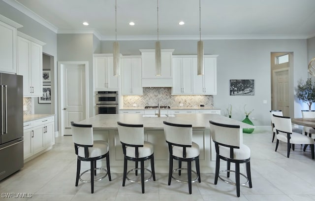 kitchen with an island with sink, white cabinetry, stainless steel appliances, decorative light fixtures, and light tile patterned floors