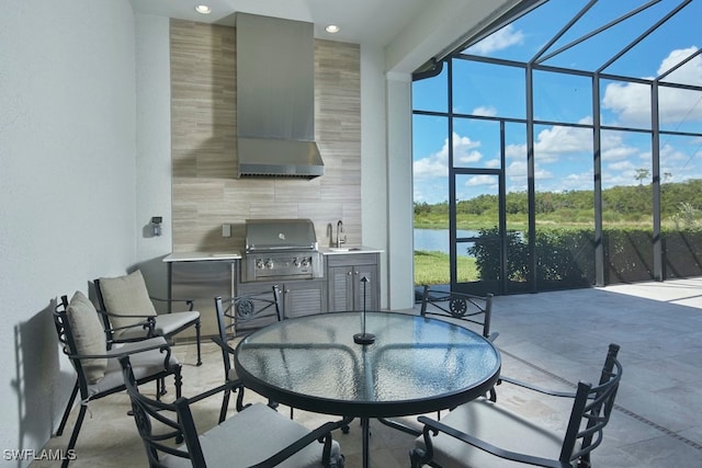 view of patio / terrace with a grill, exterior kitchen, sink, a lanai, and a water view