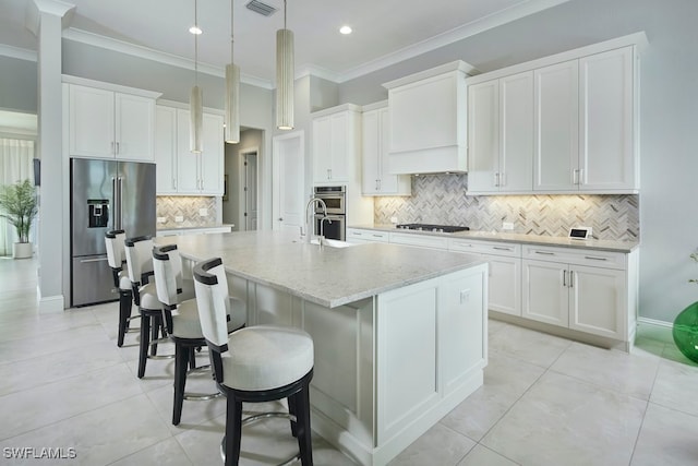 kitchen featuring decorative backsplash, white cabinetry, stainless steel appliances, and a center island with sink