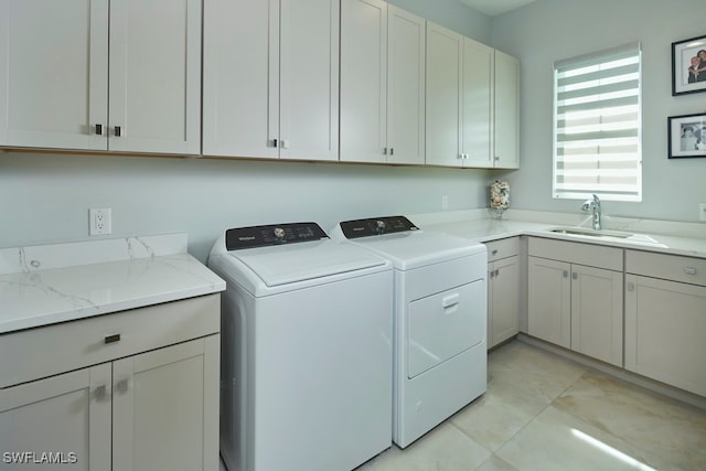 laundry room featuring sink, washing machine and clothes dryer, light tile patterned floors, and cabinets