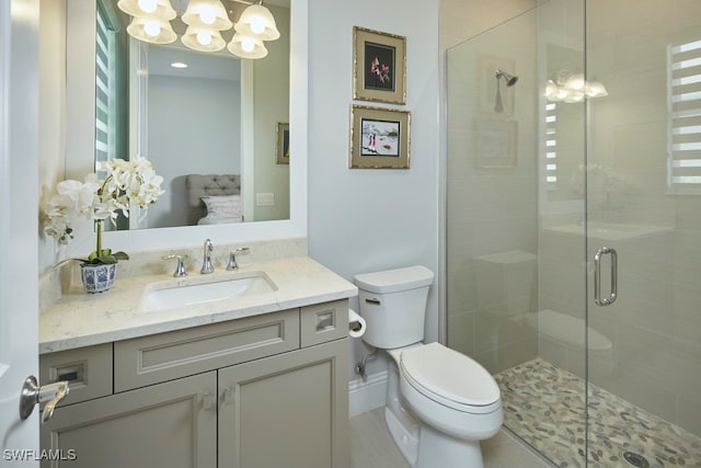 bathroom with a shower with door, toilet, vanity, a notable chandelier, and tile patterned flooring