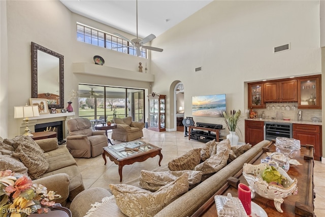 tiled living room featuring wine cooler, indoor bar, a high ceiling, and ceiling fan