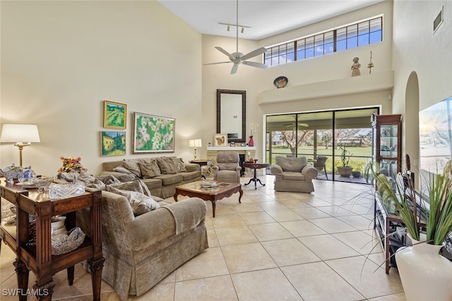 living room featuring ceiling fan, a high ceiling, and light tile patterned floors