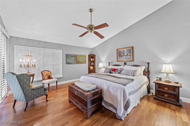 bedroom featuring lofted ceiling, light wood-type flooring, and ceiling fan with notable chandelier