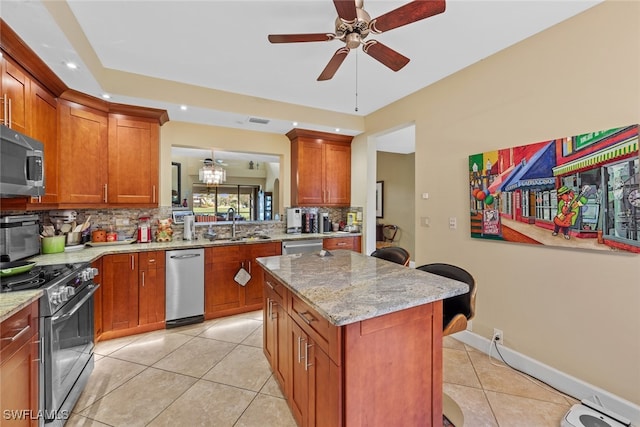 kitchen featuring a center island, light stone counters, stainless steel appliances, and tasteful backsplash