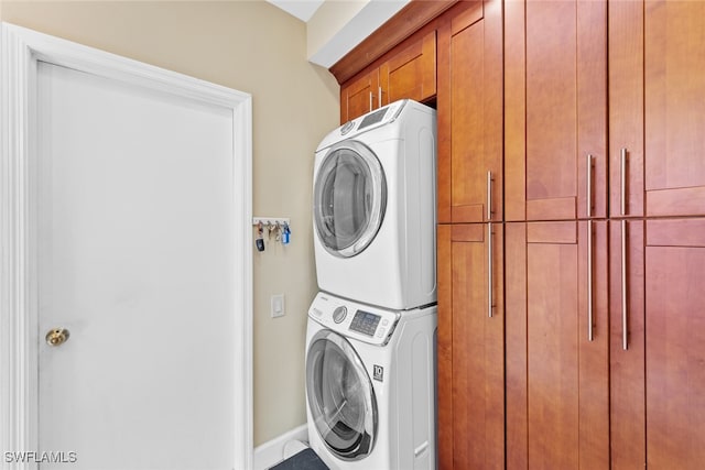 laundry room featuring stacked washer / dryer and cabinets