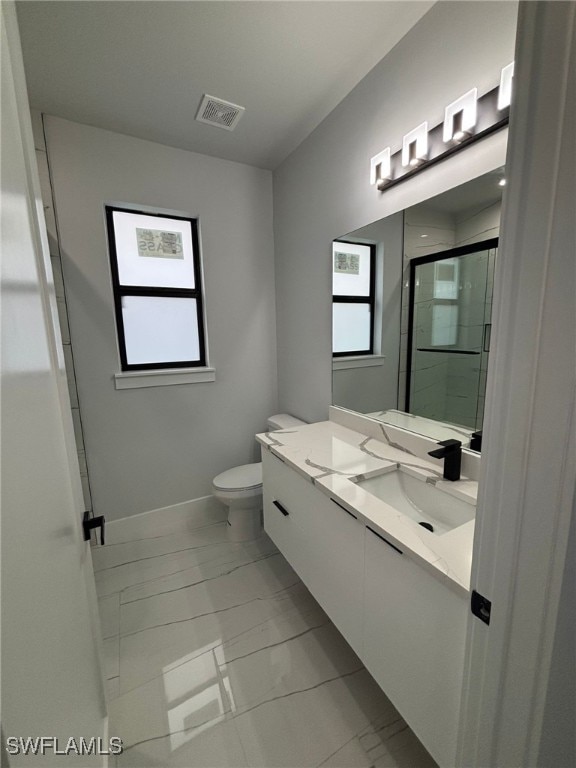 bathroom with vanity, toilet, and a shower with door