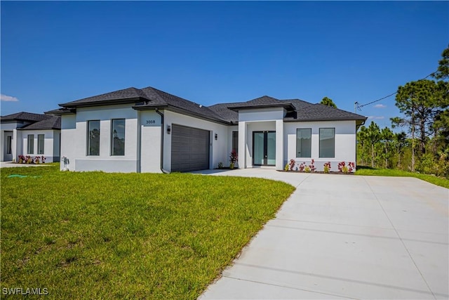 prairie-style home with a garage, driveway, a front lawn, and stucco siding