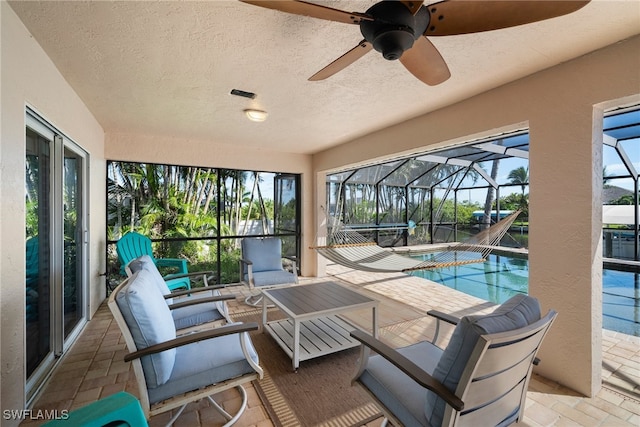 view of swimming pool featuring a patio, ceiling fan, glass enclosure, and an outdoor hangout area