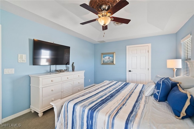 carpeted bedroom with ceiling fan and a tray ceiling