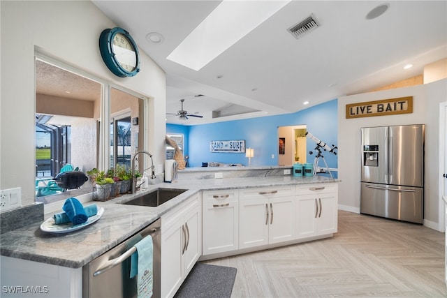 kitchen featuring appliances with stainless steel finishes, kitchen peninsula, white cabinets, and sink